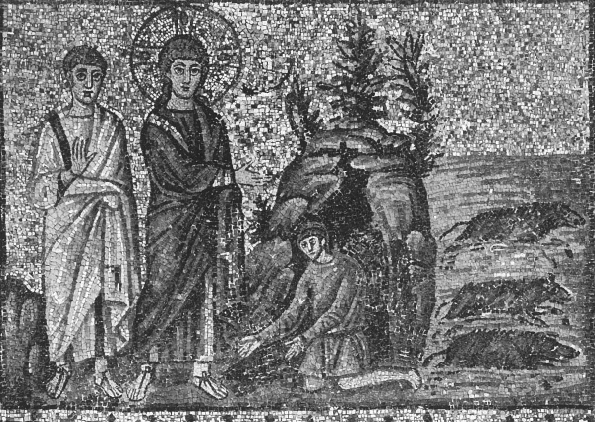 A monochrome photograph of an ancient wall mosaic in a rough, tessellated style. On the left, two standing haloed figures face right: a young, beardless Christ with a large halo, and a companion figure beside him with one hand raised to his own chest. At their feet, a smaller kneeling man reaches toward Christ with both hands. To the right, a rocky outcrop with sparse vegetation separates the group from three dark, hunched animal shapes lying along a shoreline, standing in for the herd of swine.