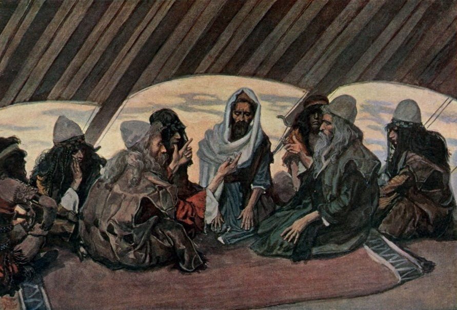 A watercolor painting of a group of bearded men seated cross-legged on a patterned rug inside a large tent, its striped canvas ceiling ribbed overhead with the pale evening sky visible through open flaps behind them. At the center, an older man in a white and blue head-covering gestures with both hands while speaking to a younger man across from him, who leans forward listening intently, one hand raised as if in mid-reply. Several other men sit around them in the circle, watching and listening, dressed in dark robes and turbans.