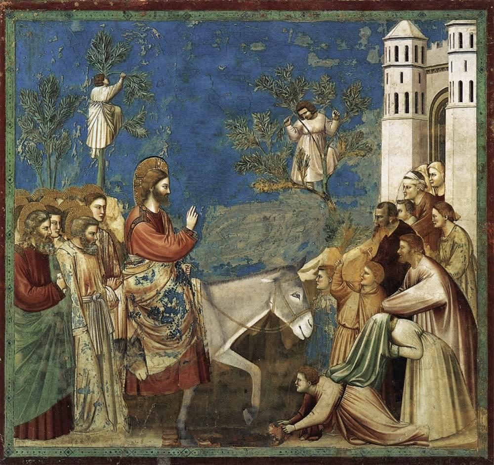 A fresco with a deep blue sky and a green painted border. Christ, haloed and in a red mantle, rides a single grey donkey from left to right, raising his hand; the disciples follow close behind him on the left. On the right, townspeople crowd out of a white city gate flanked by two tall towers; two of them bend to the ground in the foreground spreading cloaks in the road. Two boys have climbed trees behind the donkey and are cutting branches. Patches of the blue background have flaked away