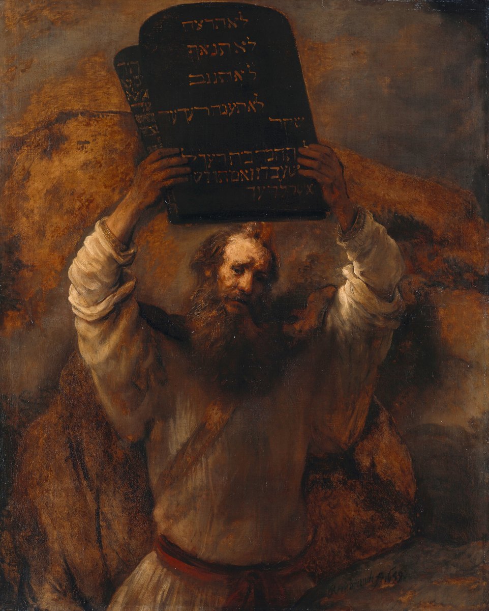 An old man in a pale robe raises a dark stone tablet above his head with both hands, his face lowered and shadowed beneath it. The tablet facing the viewer carries four lines of gold Hebrew lettering; a second tablet stands edge-on behind it at the left, turned away, its writing reduced to a narrow strip