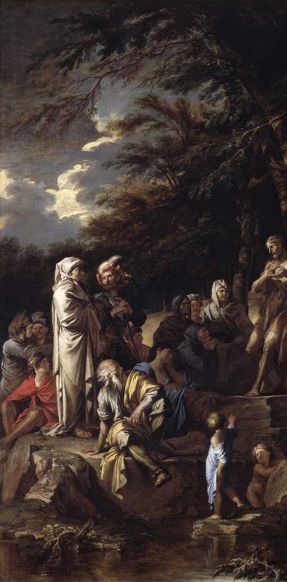 A tall, narrow landscape painting dominated by dark, wind-bent trees against a dramatic sky of grey clouds breaking to light. In the lower left, a mixed crowd sits and leans on a rocky outcrop: elderly bearded men, women in draped fabric, a soldier in armor, a bare-shouldered woman in red, children. At the right edge, a standing figure in rough dress, partly shadowed by the trees, gestures with one raised hand. In the lower right, two small children play at the edge of a stream below the rock.