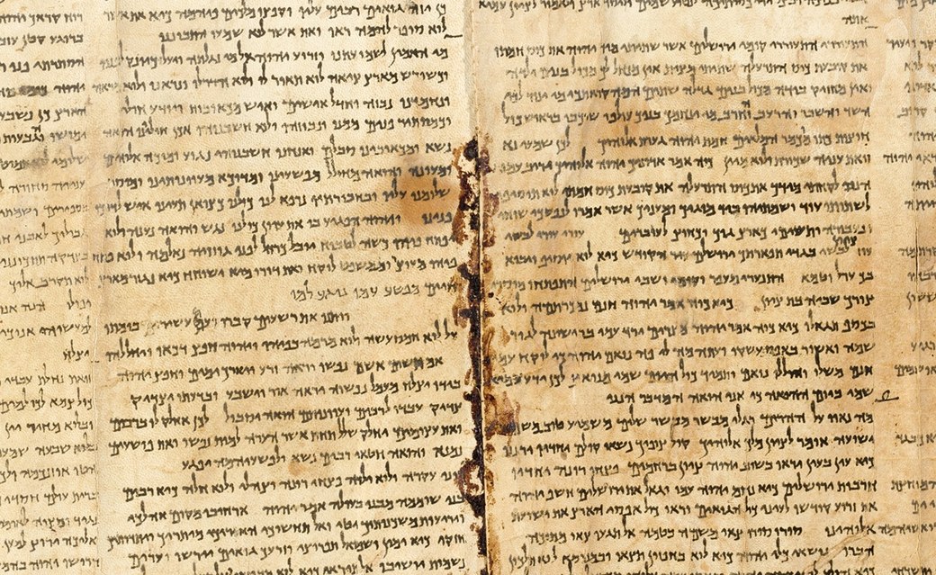 Two columns of the Great Isaiah Scroll from Qumran — dense hand-written Hebrew on warm parchment, with an ancient crack running between the sheets