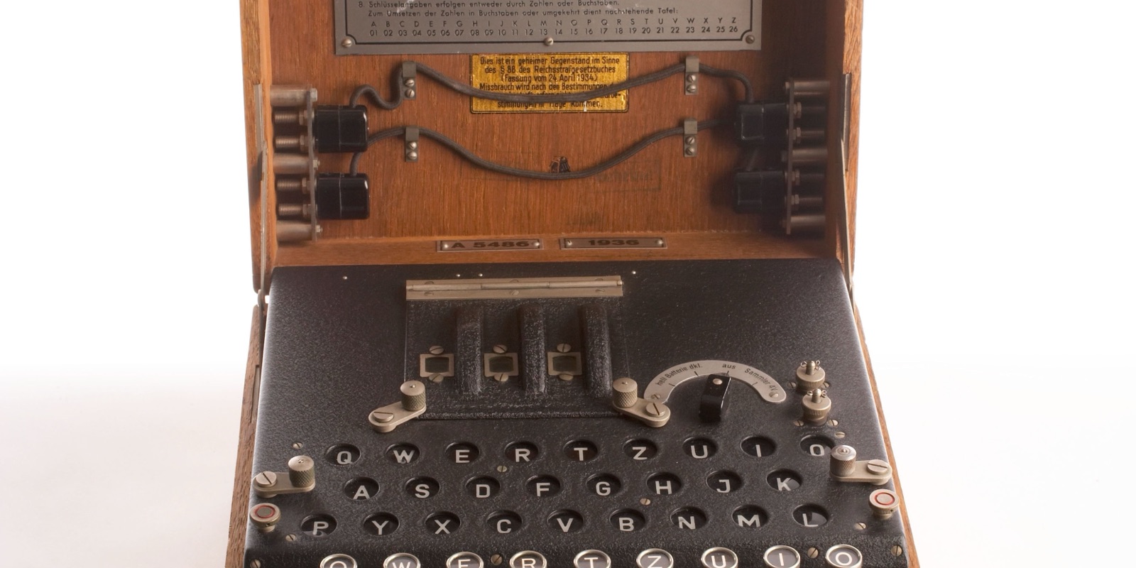 A German Enigma cipher machine displayed open, showing its wooden case, plugboard, keyboard and rotor assembly, photographed against a plain white background
