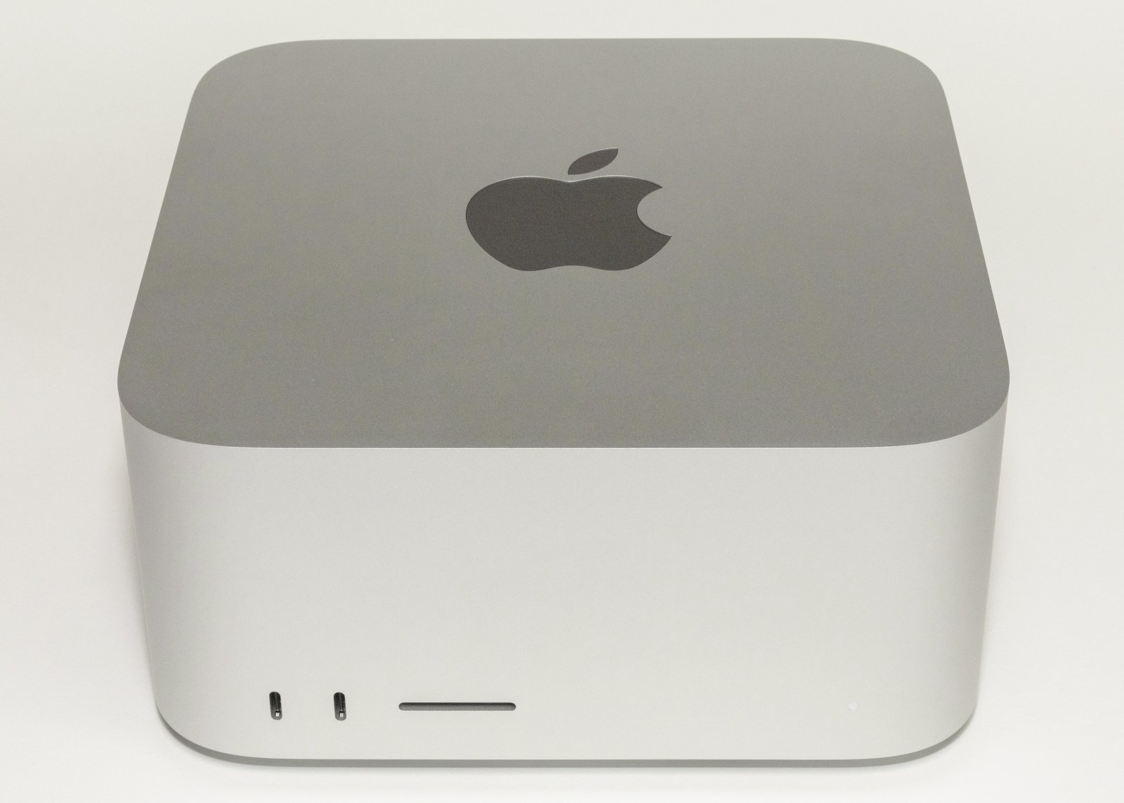A Mac Studio desktop computer, a small square aluminum box with rounded corners and an Apple logo on top, photographed on a plain white background