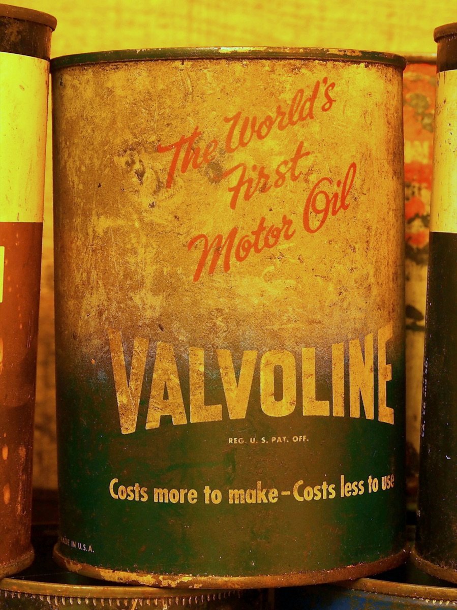 An old tin Valvoline motor oil can, marketed on its own label as "the world's first," displayed in a glass museum case