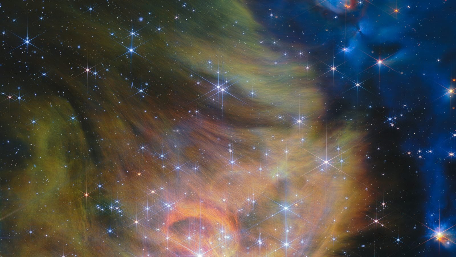 A dense, glowing gold and orange cloud of gas and dust shot through with bright, diffraction-spiked stars, fading into a dark blue starfield to the right
