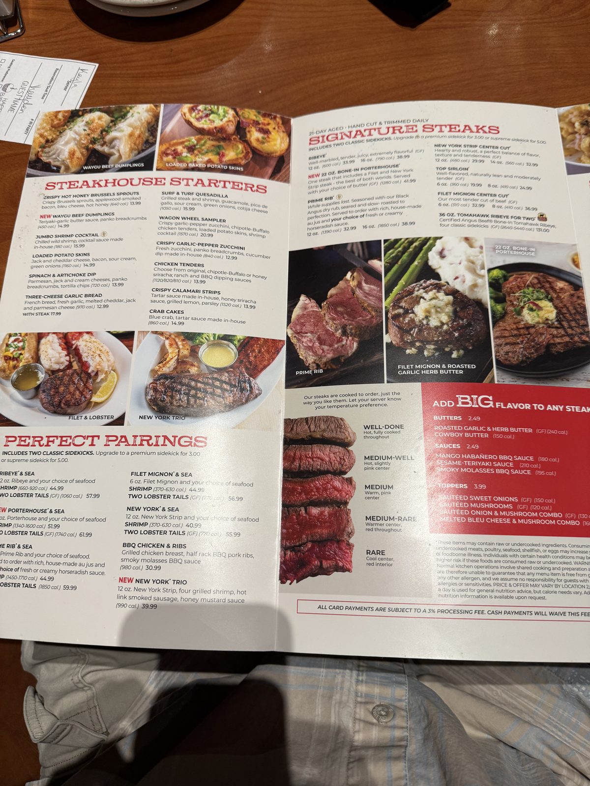 The Steakhouse Starters and Signature Steaks pages of the menu, listing appetizers like crab cakes and loaded potato skins on one side, and steak options — ribeye, bone-in porterhouse, prime rib, New York strip, top sirloin, filet mignon and a tomahawk ribeye for two — with prices and calorie counts on the other, alongside a doneness chart from well-done to rare