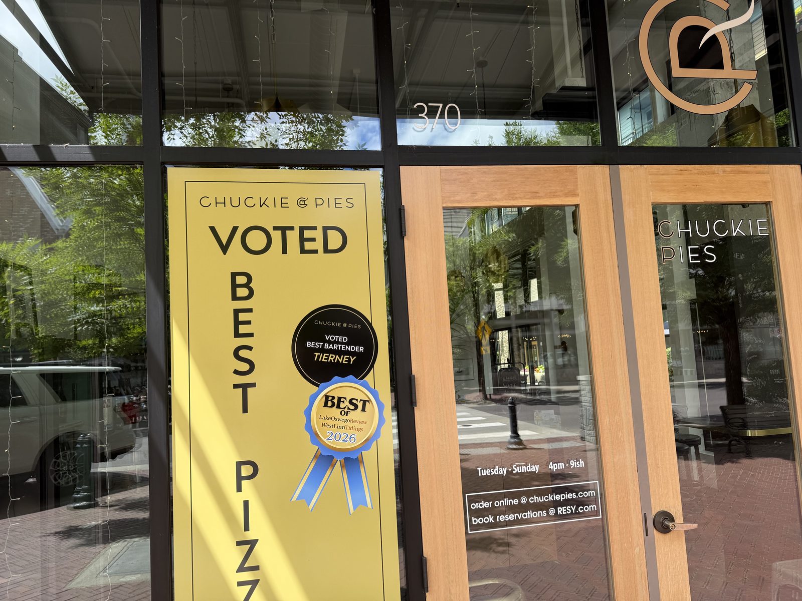 A yellow poster on the door reading Chuckie Pies, Voted Best Pizza, beside two award ribbons