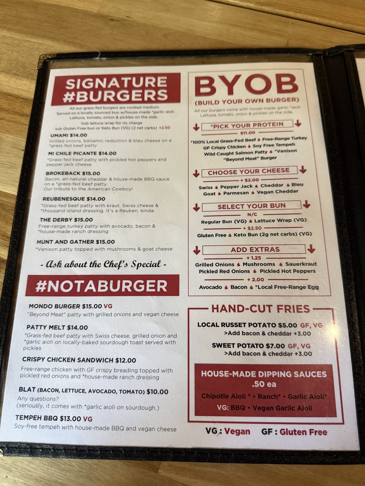 The Dick's Primal Kitchen menu, showing Signature Burgers from fourteen to fifteen dollars, a Build Your Own Burger section starting at eleven dollars with protein choices including grass-fed beef, free-range turkey, wild-caught salmon, tempeh and venison, and hand-cut fries