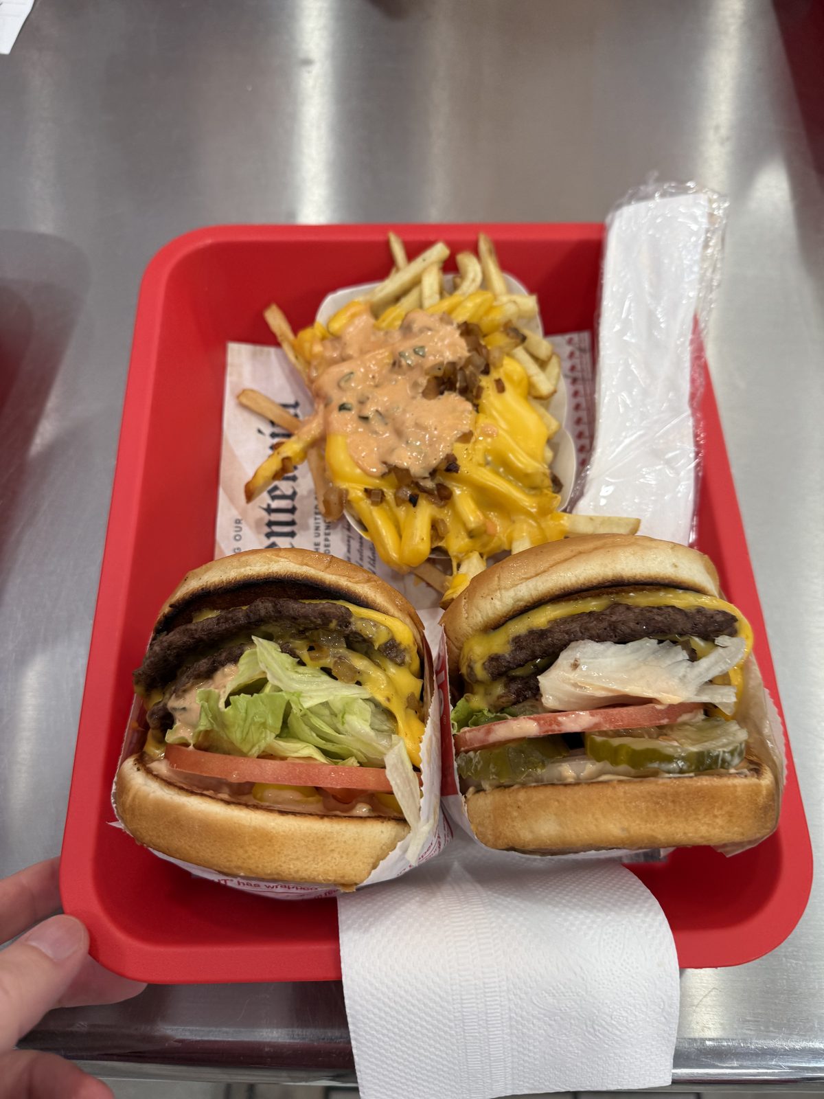 A close cross-section of two halved Double-Double cheeseburgers, showing two beef patties, melted American cheese, spread, lettuce, tomato and pickle stacked between a toasted bun
