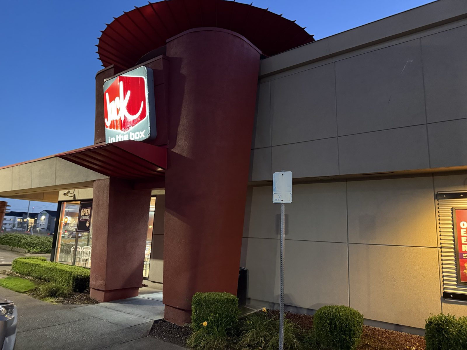 The Jack in the Box sign and entrance at dusk, red awning and column against a clear evening sky