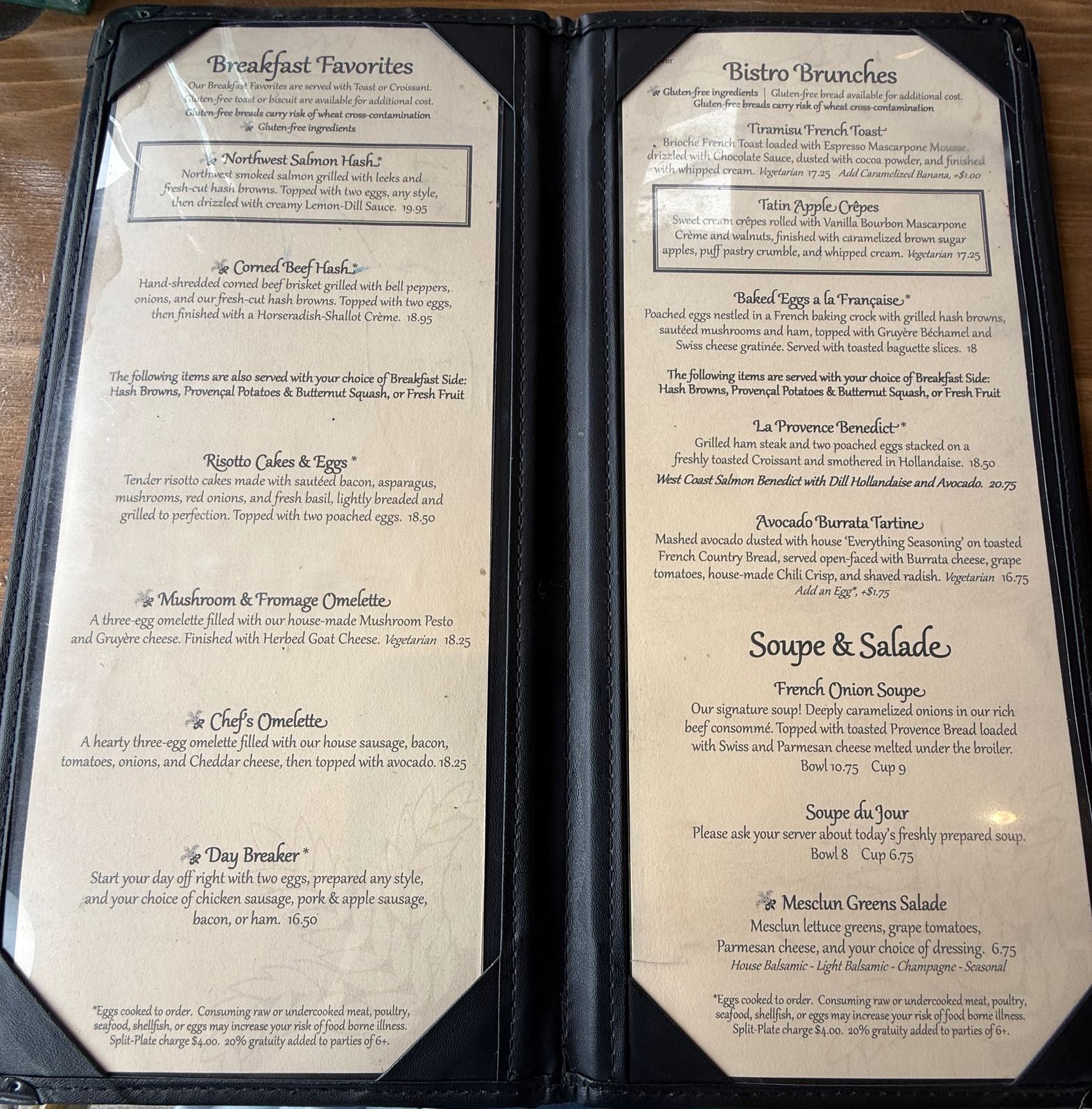 The open breakfast menu at La Provence, left page headed Breakfast Favorites listing Northwest Salmon Hash, Corned Beef Hash, Risotto Cakes and Eggs, omelettes and the Day Breaker; right page headed Bistro Brunches listing Tiramisu French Toast, Tatin Apple Crêpes, Baked Eggs à la Française, La Provence Benedict at 18.50 and West Coast Salmon Benedict at 20.75