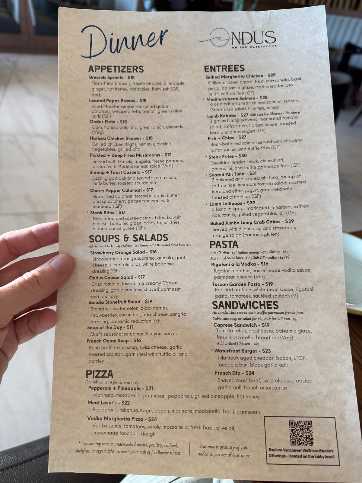 The Ondus on the Waterfront dinner menu held up for the camera, listing appetizers, soups and salads, pizza, entrees, pasta, and sandwiches