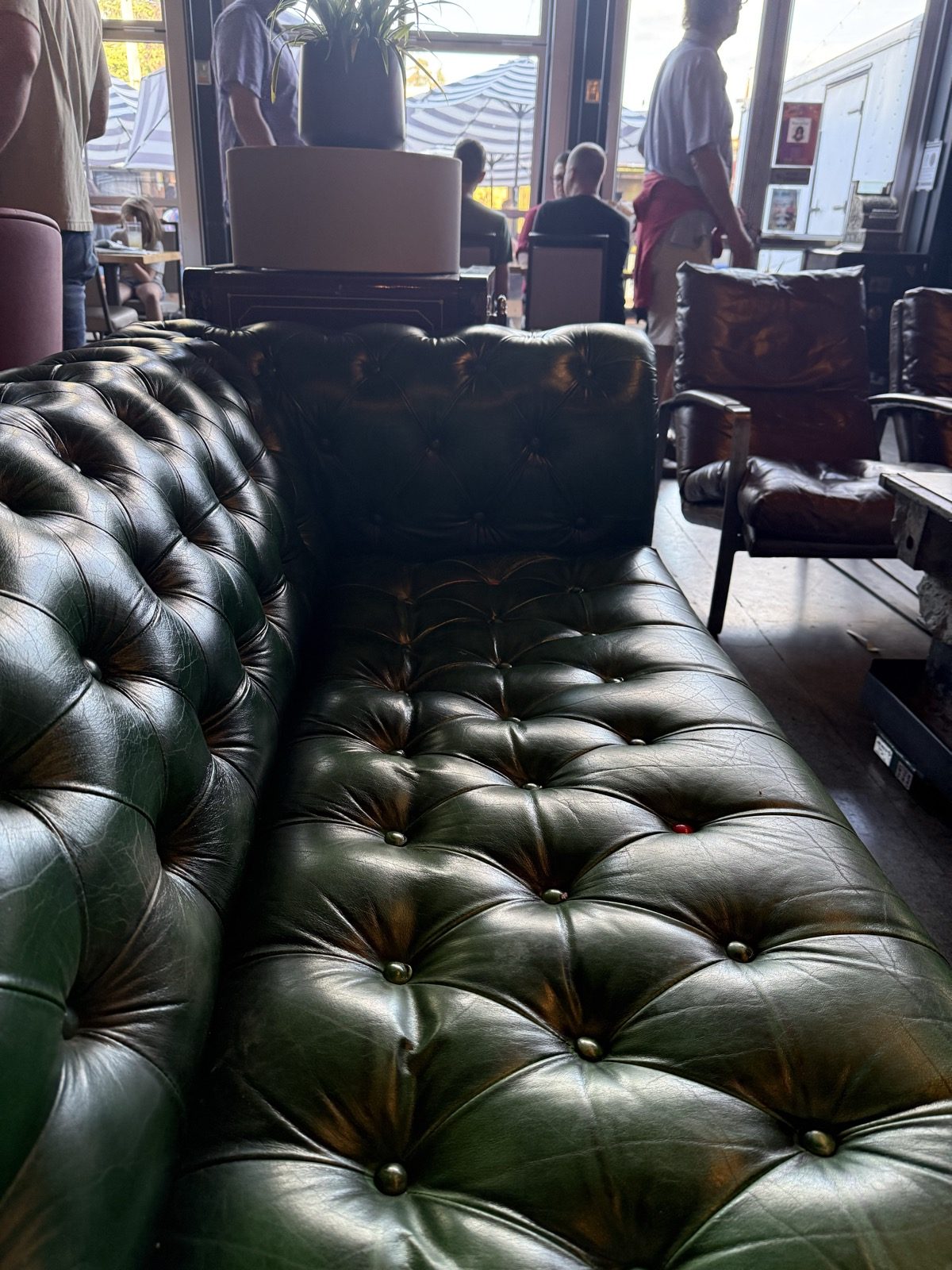 A row of green tufted leather chesterfield couches in a lounge area at The Heist in Portland, Oregon