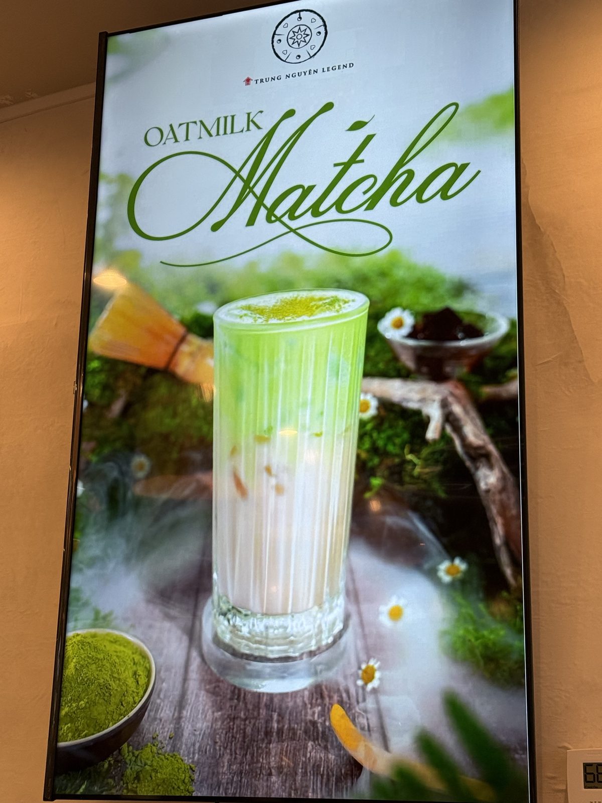 Digital menu board for Oatmilk Matcha, a pale green iced matcha drink on a mossy backdrop