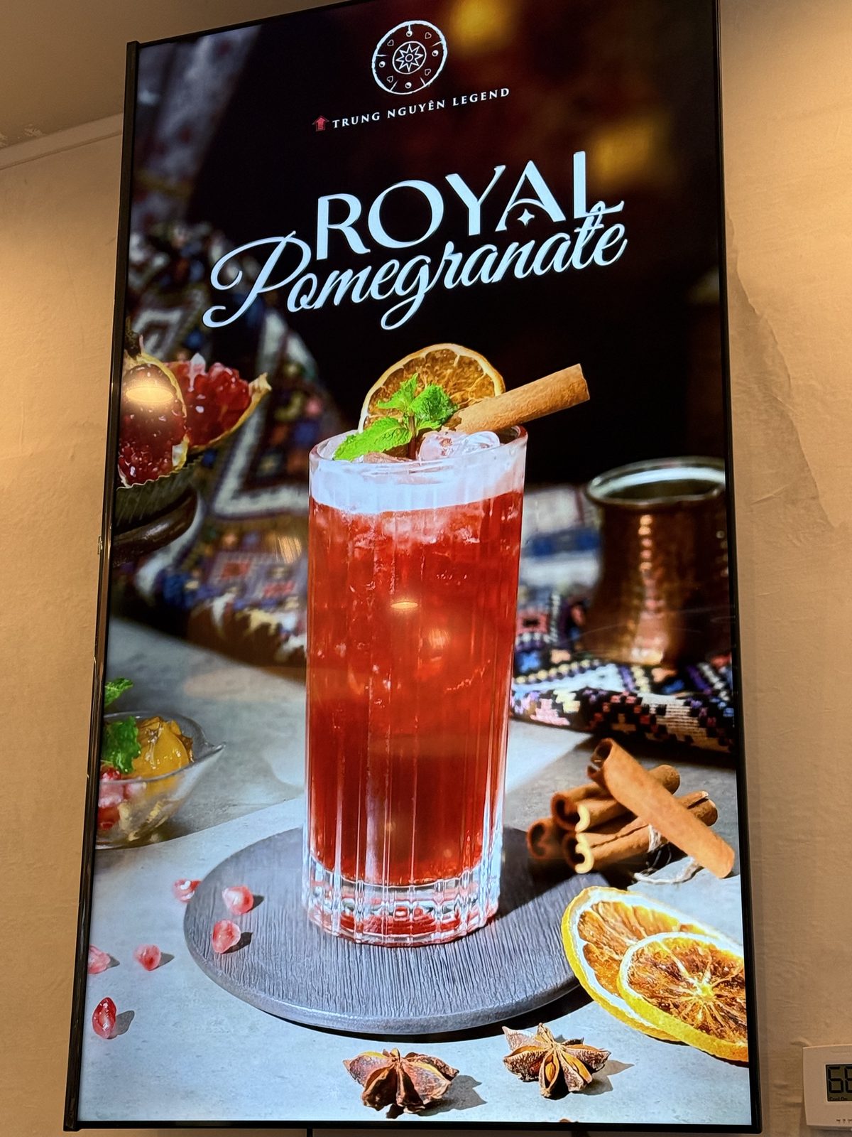 Digital menu board for Royal Pomegranate, a tall red iced drink garnished with a dried orange wheel, mint and a cinnamon stick