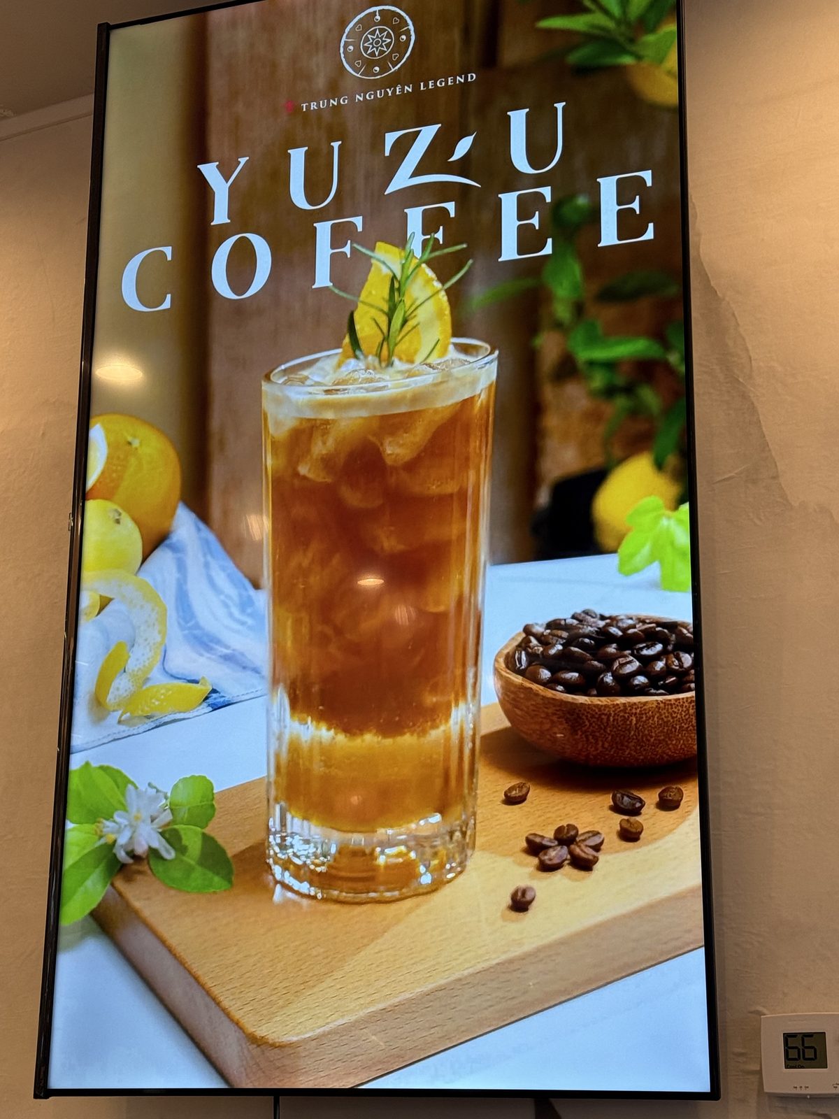 Digital menu board for Yuzu Coffee, an iced tea-colored drink garnished with a yuzu twist next to whole coffee beans