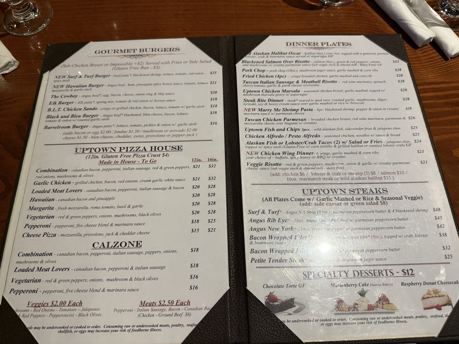 The menu page listing seven gourmet burgers from the Barrelroom Burger at sixteen dollars up to a Surf and Turf at twenty-five, alongside the Uptown Pizza House section of twelve and sixteen inch pizzas and calzones